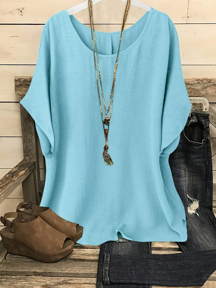 Sky blue loose summer top on hanger with necklace, sandals, and jeans on rustic bench.