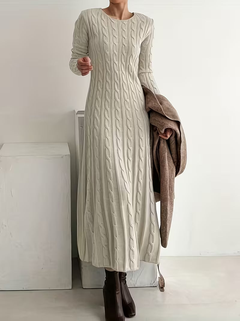 Elegant off-white maxi dress with a fitted, textured design, paired with brown boots, in a minimalist indoor setting.