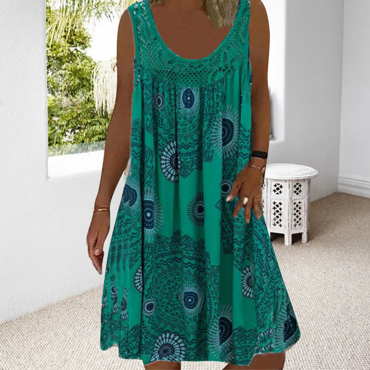 Woman in green printed dress in a luminous room with garden view.