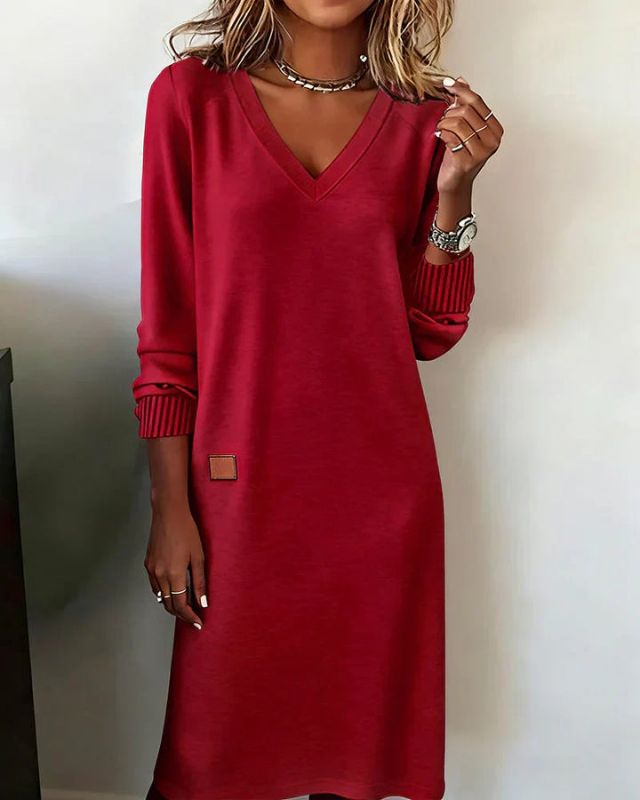 Red cozy dress with V-neck and long sleeves, worn indoors.