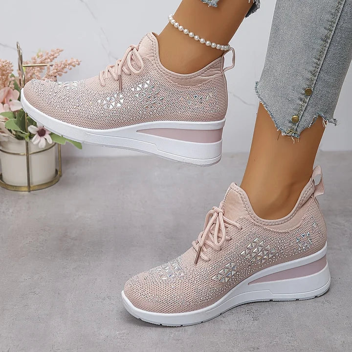 Light pink orthopedic sneakers showcasing glossy features, styled with jeans, in a soft-lit environment.
