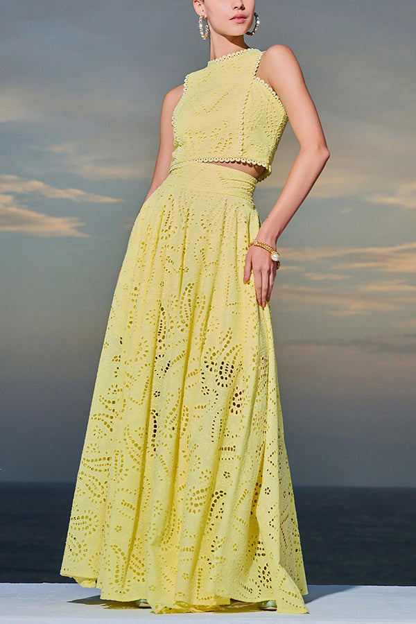 Woman in a yellow embroidered top and high-waist maxi skirt posing outdoors against a sunrise background.