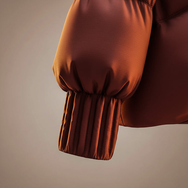 Close-up of puffed brown coat sleeve with ribbed cuff detail in a studio setting.
