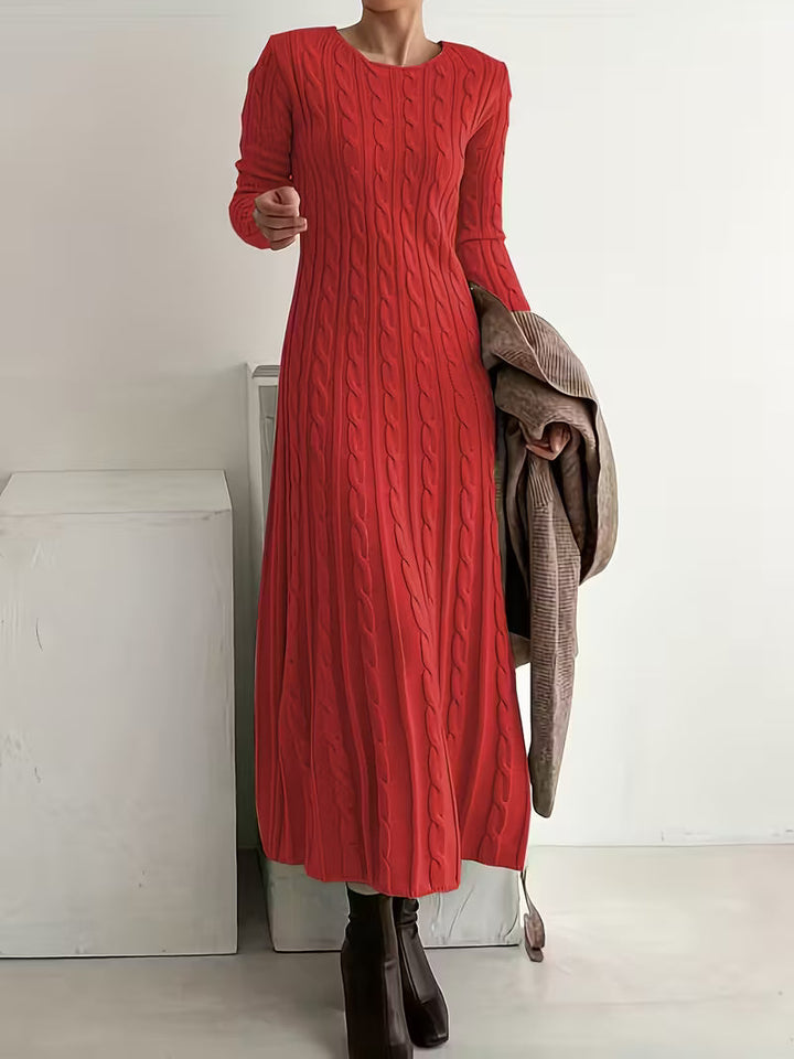 Chic red maxi dress with a fitted, textured look, styled with brown boots, in a minimalist indoor environment.