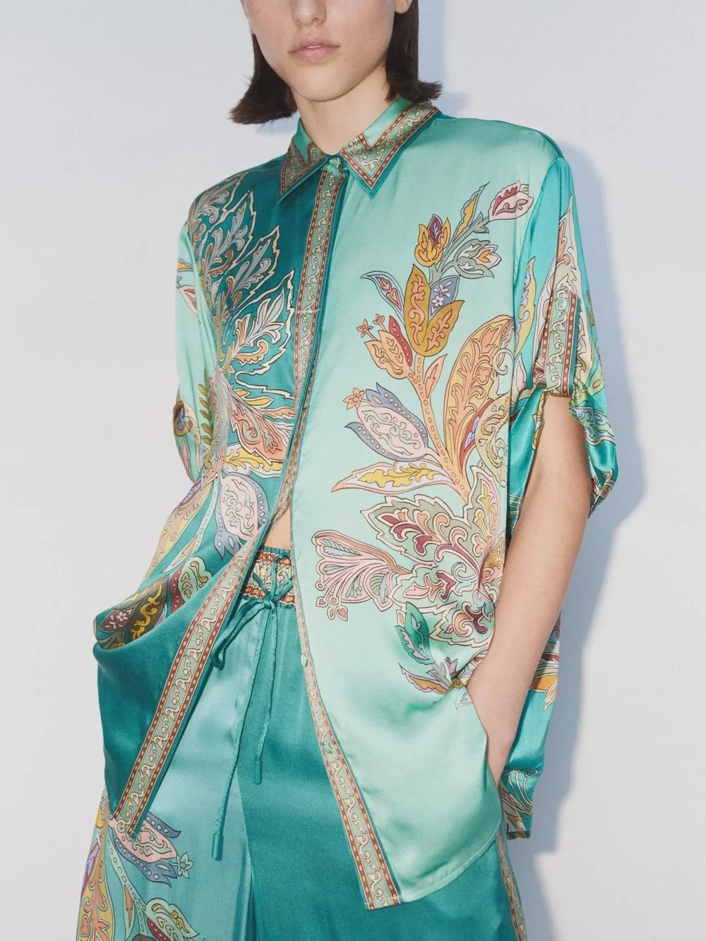 Green two-piece set with detailed paisley design, pocketed shirt and elastic waist pants, studio shot with white backdrop.