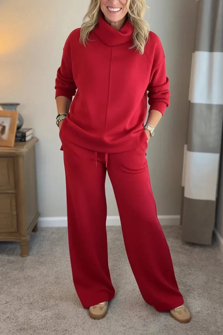 Woman wearing a red comfortable set with long sleeves and wide-leg pants, standing in a cozy, carpeted room.