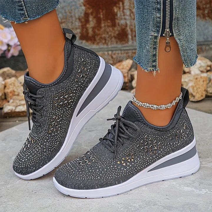 Gray orthopedic sneakers with intricate sparkle detailing, worn outdoors with rocky background.