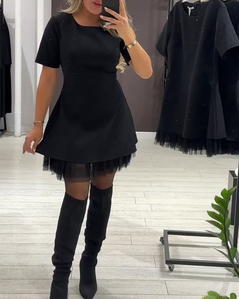 Black dress with subtle sparkle, tulle hemline, and long boots. Shop backdrop with contemporary design.
