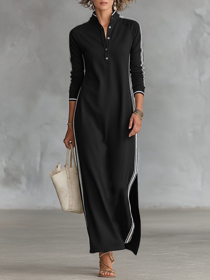 Full view of black maxi dress with white stripes, worn by a person holding a tote. Indoor background.