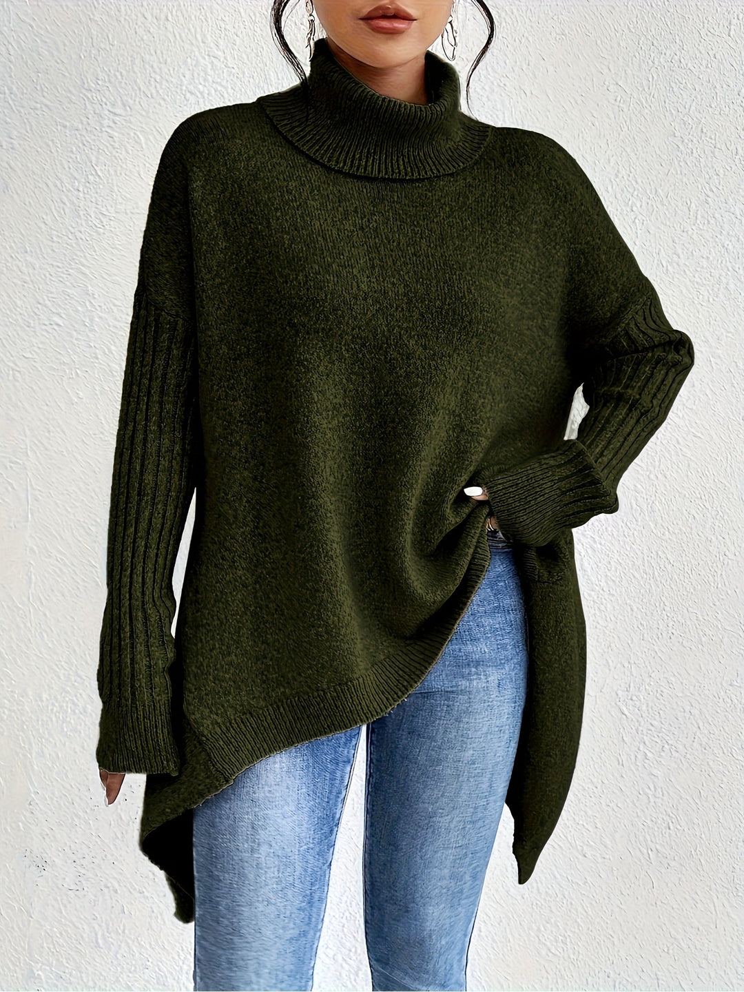 Green sweater with turtleneck and long sleeves, styled with jeans, against a white backdrop.