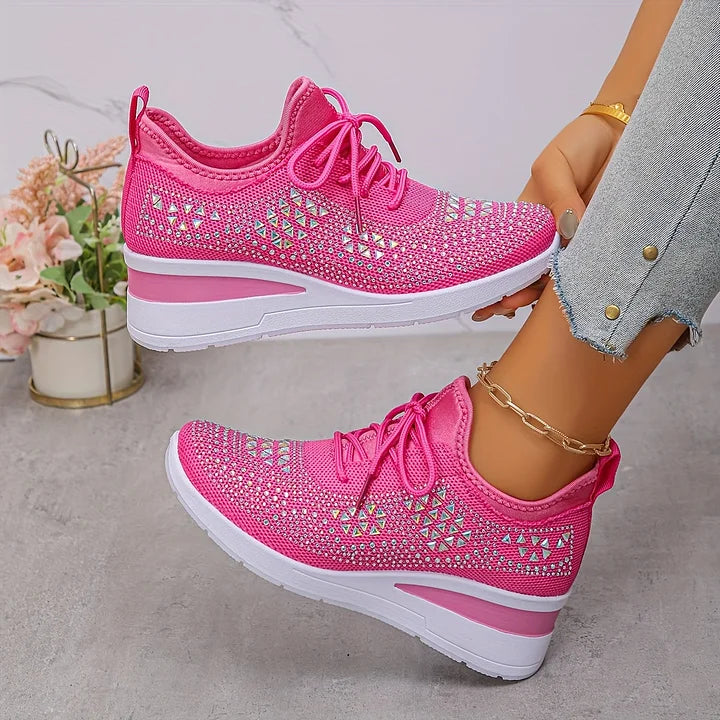 Bright pink sparkling orthopedic sneakers worn with fitted jeans, in a light tonal room with floral touches.