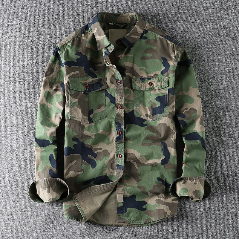 Green urban camo shirt lying flat on a textured gray surface, with folded sleeves.