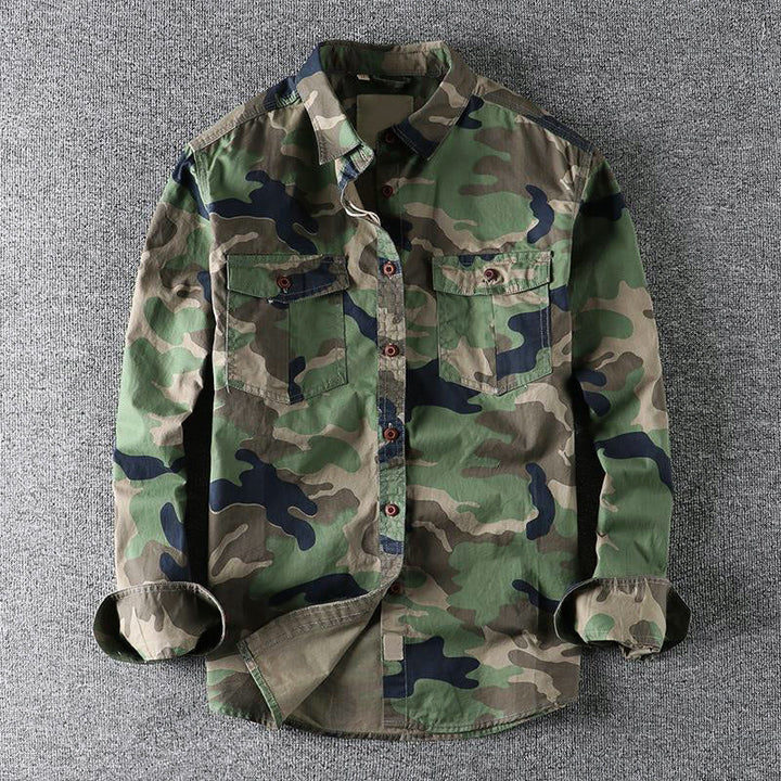 Green urban camo shirt lying flat on a textured gray surface, with folded sleeves.