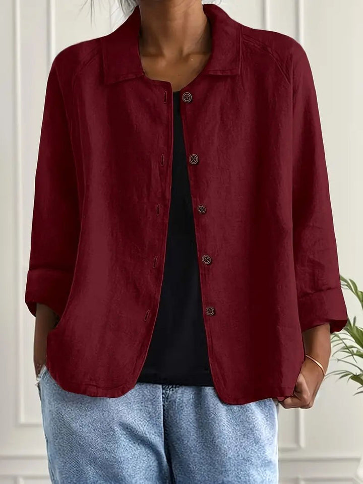 Deep red long sleeve top with button-down front, worn over a black shirt. Indoors, white paneled wall backdrop.