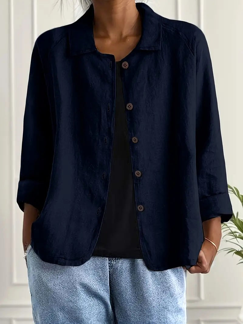 Navy blue long sleeve top with button-down front, worn over a black shirt. Indoors, white paneled wall backdrop.