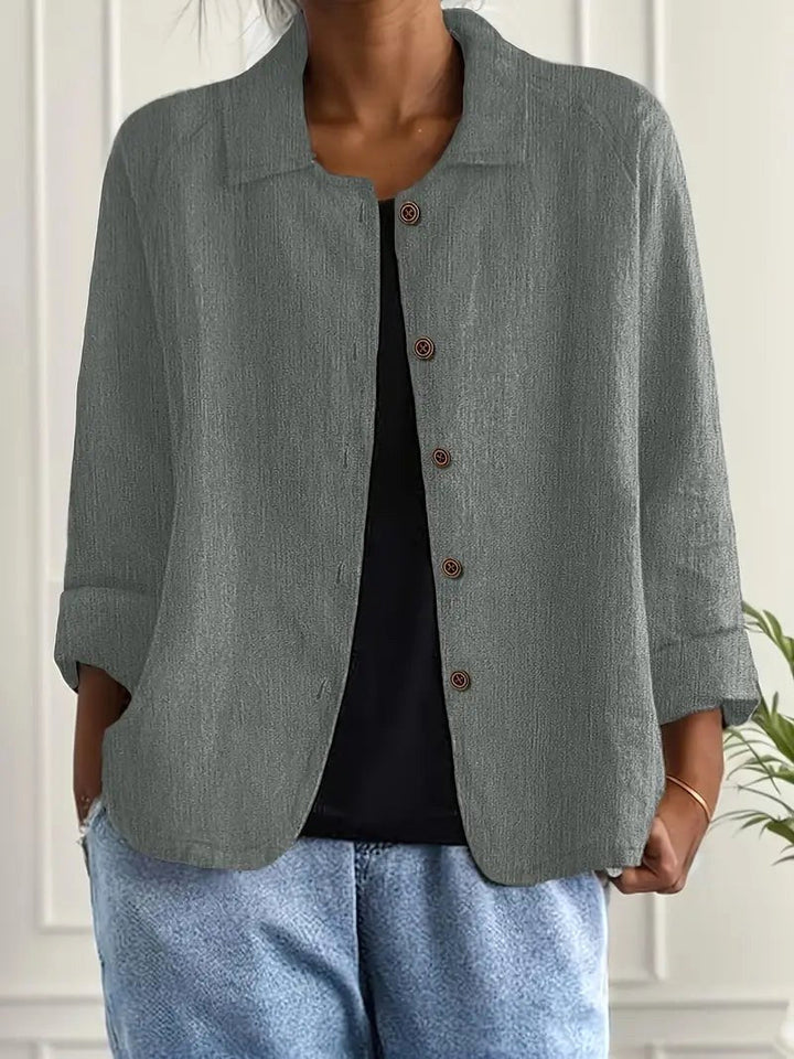 Heather gray long sleeve top with button-down front, worn over a black shirt. Indoors, white paneled wall backdrop.