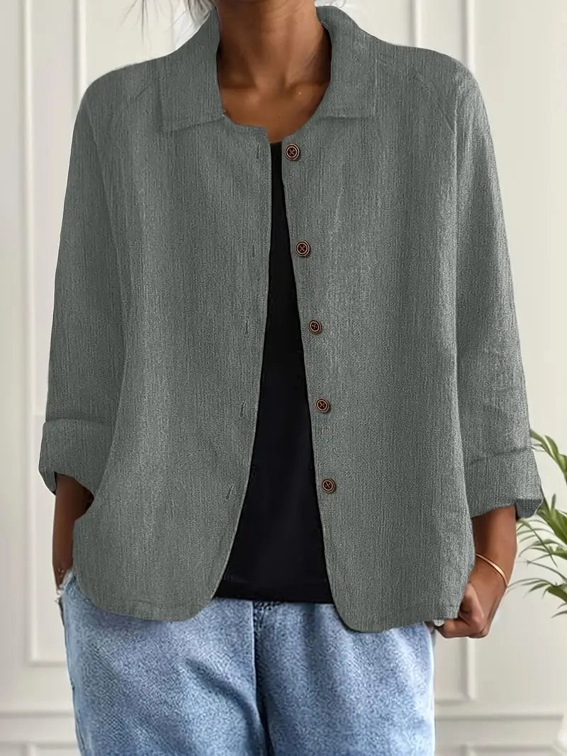 Dark gray long sleeve top with button-down front, worn over a black shirt. Indoors, white paneled wall backdrop.