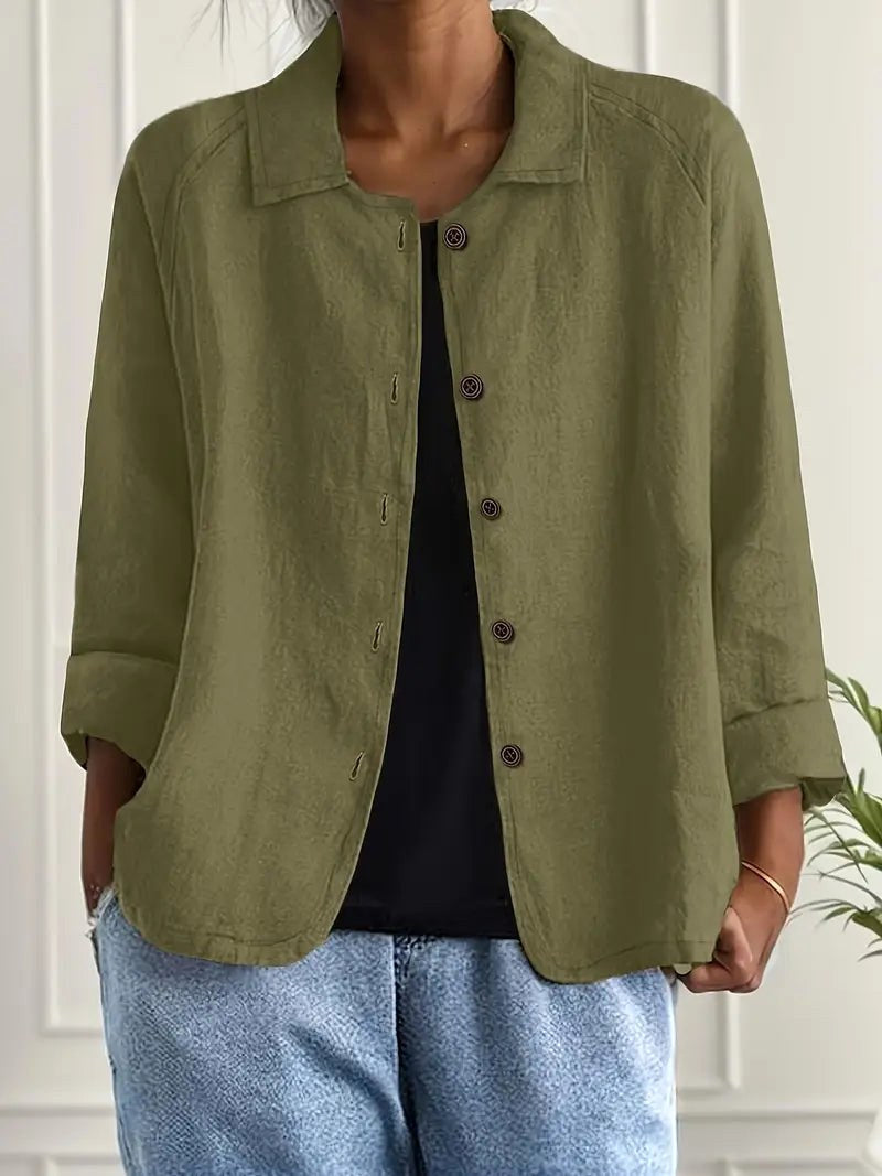 Olive green long sleeve top with button-down front, worn over a black shirt. Indoors, white paneled wall backdrop.
