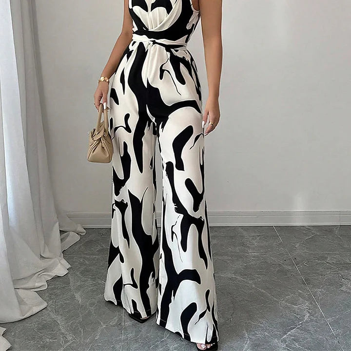 Side view of patterned black and white jumpsuit on a model in a light-filled room with curtain details.