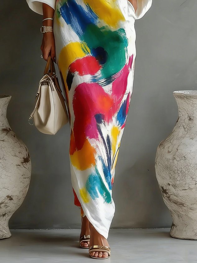 Close-up of a colorful maxi dress with abstract splashes of vibrant colors, styled with a bag, in a minimalistic room.