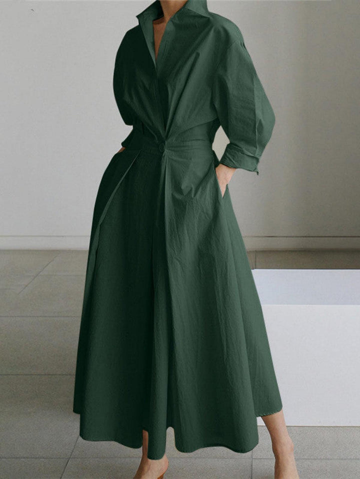 Olive green midi dress with button lapel, hands in pockets, worn indoors on tile floor.