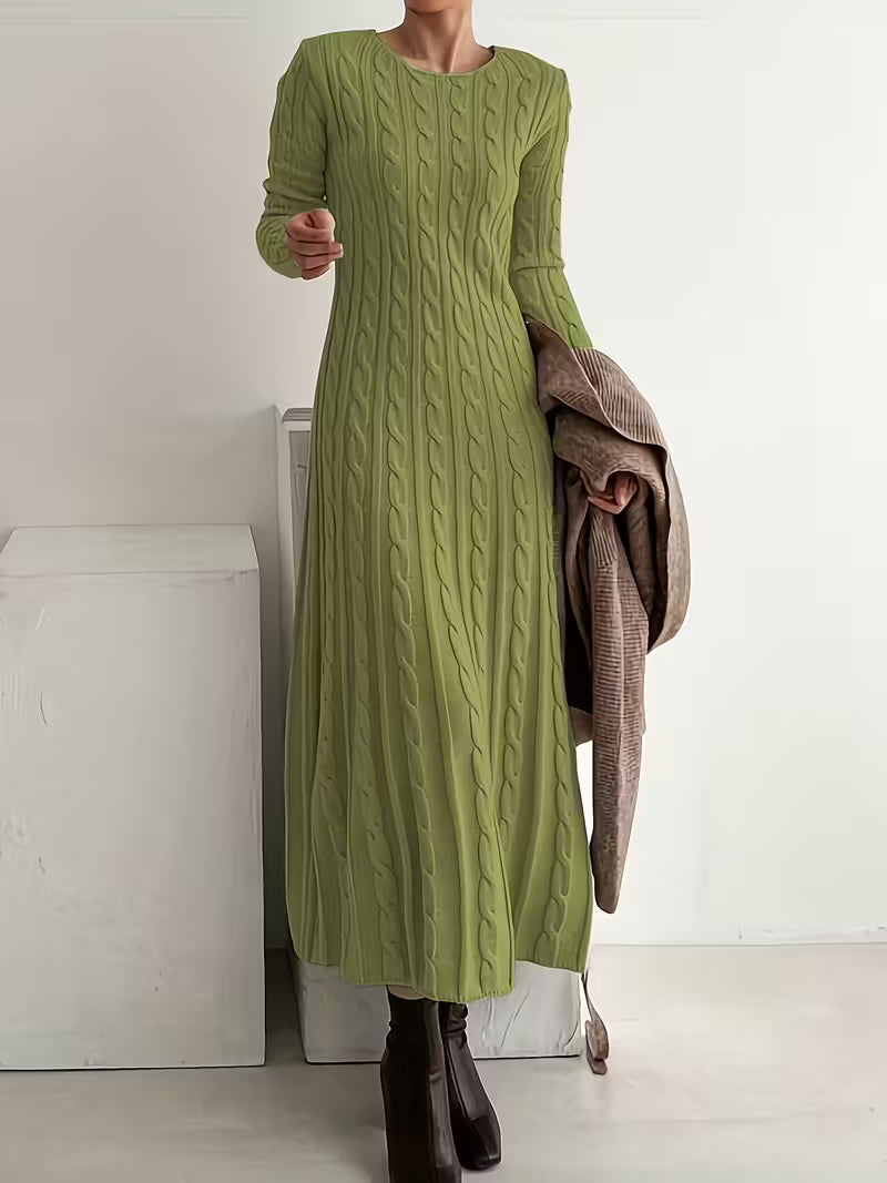 Stylish green maxi dress featuring a textured pattern, complemented by brown boots, in a simple indoor background.