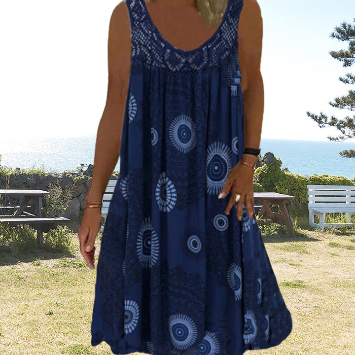 Woman in navy printed dress standing outdoors near the ocean.