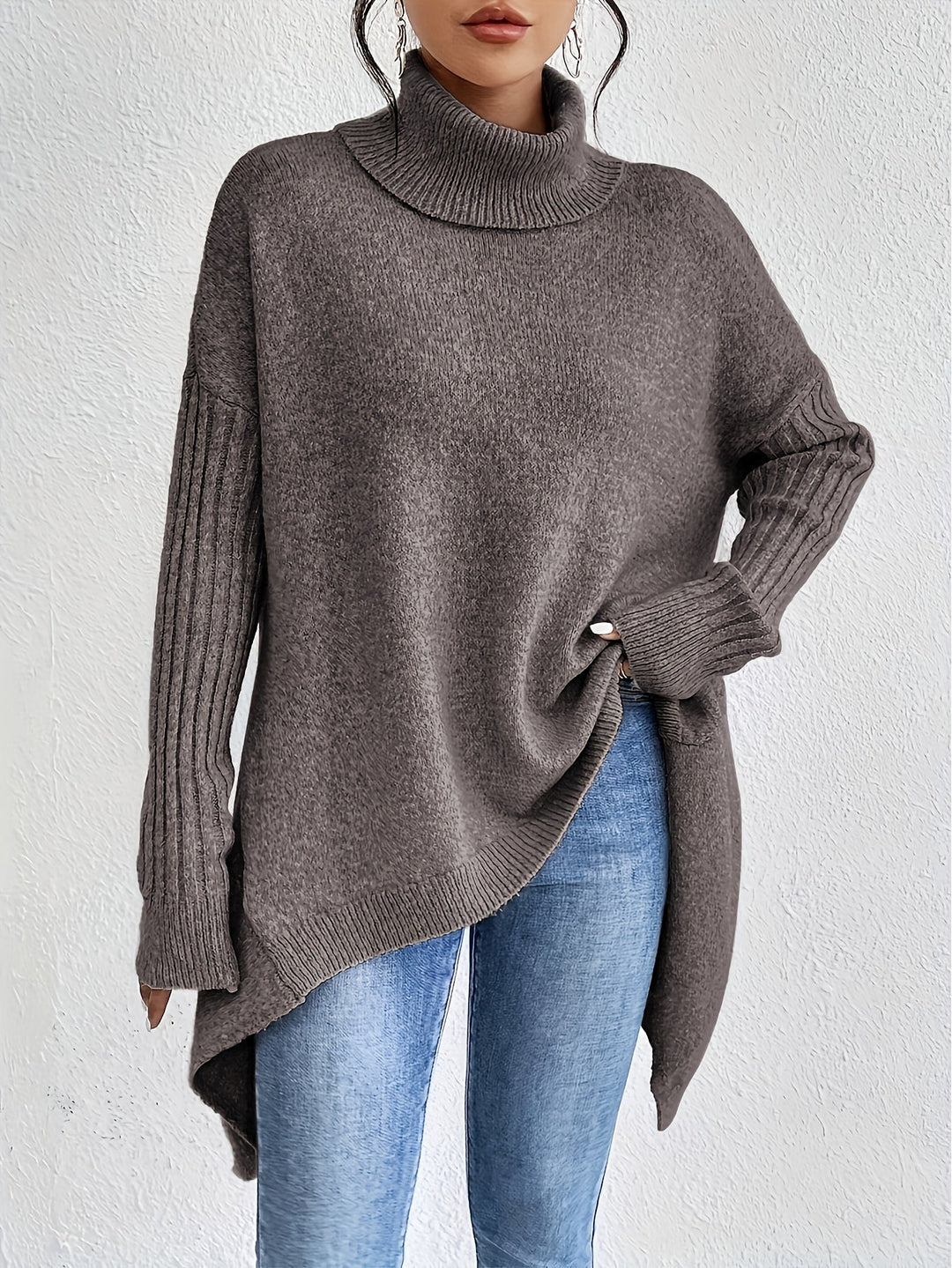 Brown sweater with turtleneck and long ribbed sleeves, styled with jeans, against a white backdrop.
