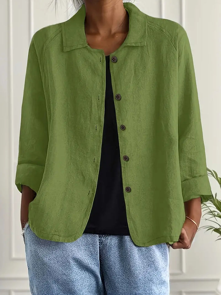 Bright green button-up top with rolled sleeves, worn over black shirt in an indoor setting.