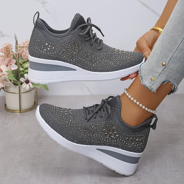 Gray orthopedic sneakers featuring a textured look, worn with jeans and surrounded by a soft indoor setting.