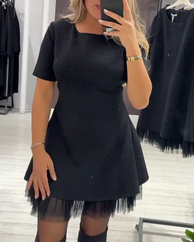 Sleek black dress with shimmering accents and delicate tulle, worn in a stylish retail environment.