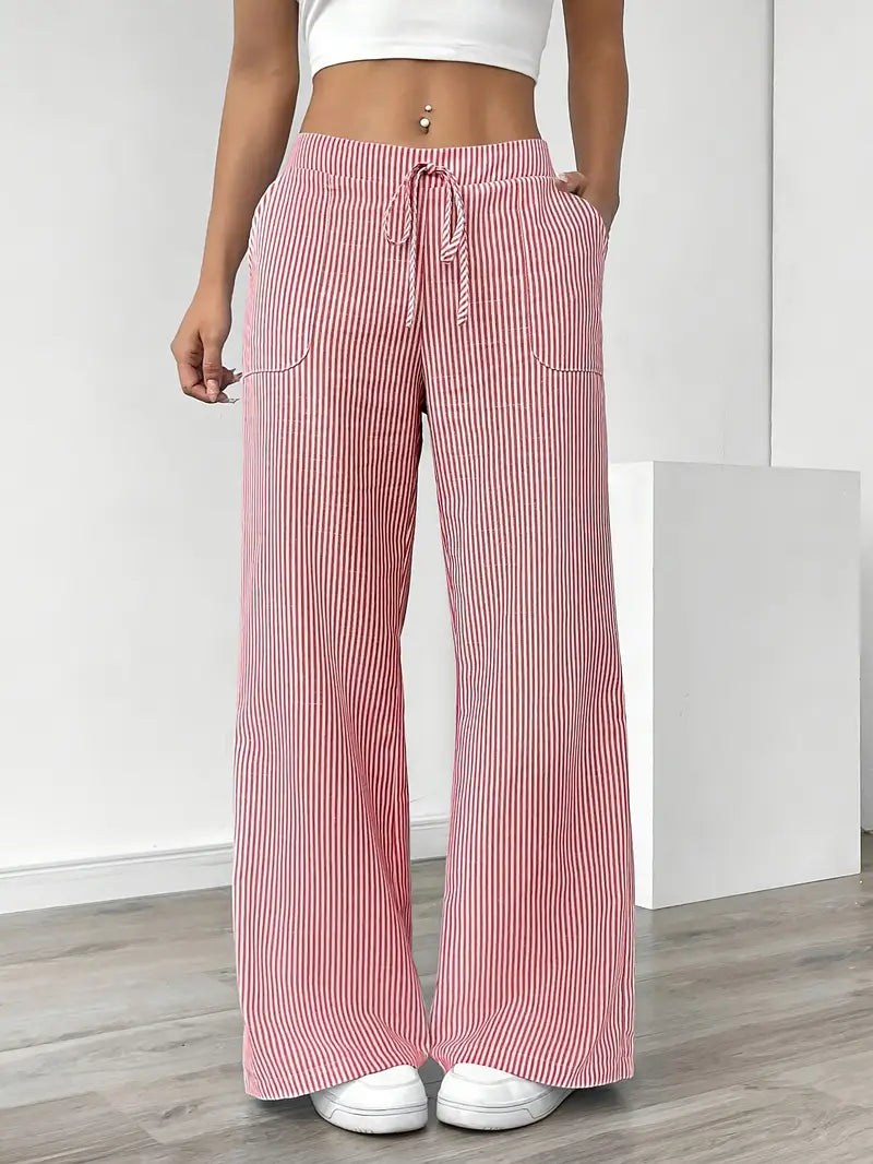 Red and white striped relaxed pants with drawstring waist, modeled indoors, paired with white sneakers and crop top.