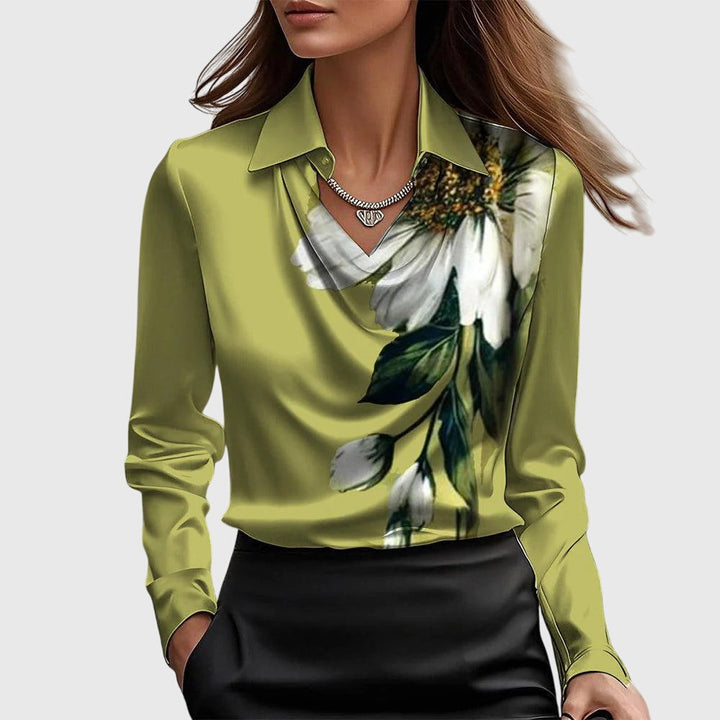 Olive green blouse with a white floral print, draped neckline, long sleeves, matched with a black skirt against a simple background.