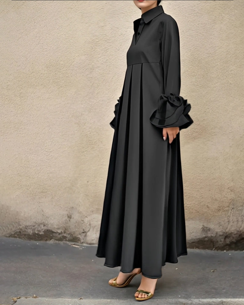 Side view of black flared maxi dress with ruffled sleeves, set against a neutral textured wall.
