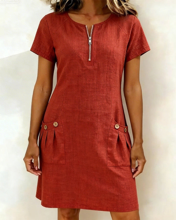 Red short-sleeve dress with zipper front and buttoned pockets in a studio setting.