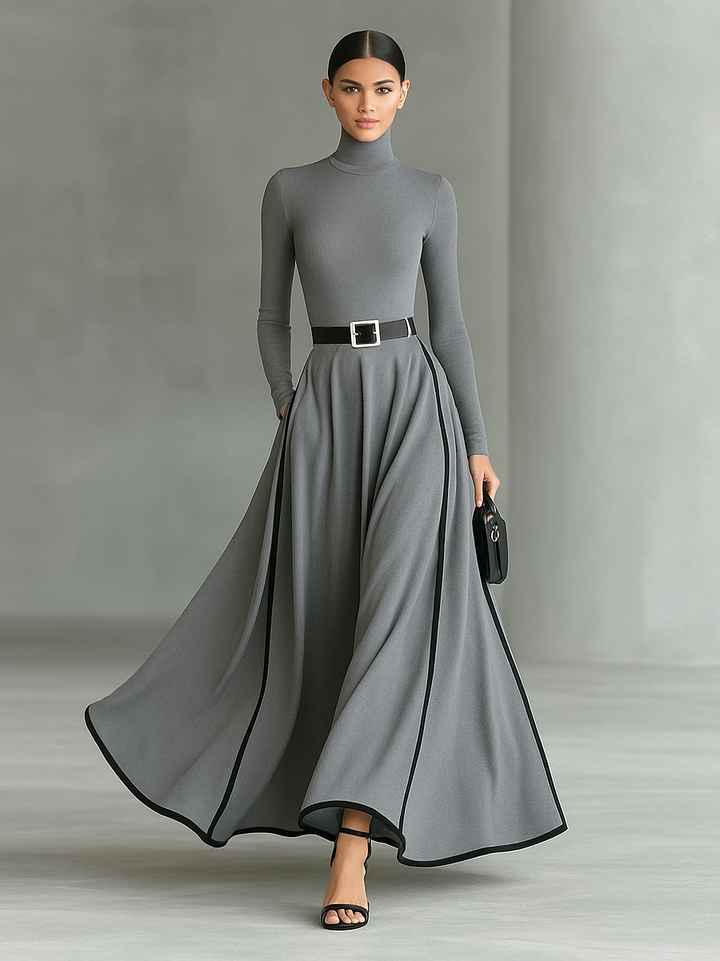 Sophisticated gray long sleeve maxi dress with black trim, black belt, flowing skirt; studio environment.