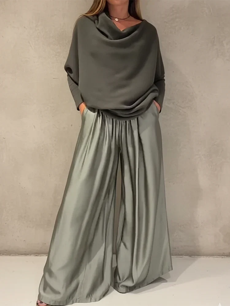 Person wearing a sleek gray off-shoulder set against a plain wall background.