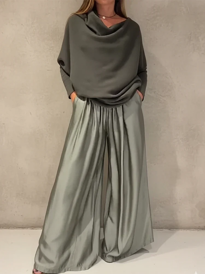 Person wearing a sleek gray off-shoulder set against a plain wall background.