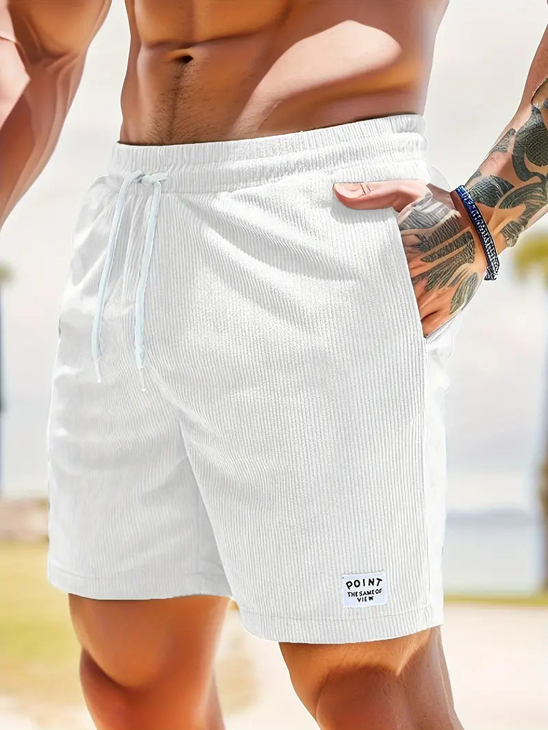 Close-up of white swimming trunks with drawstring, worn by model on a beach scene.