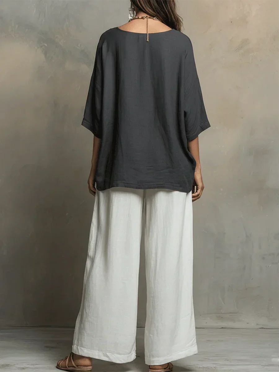 Back view of dark top and white pants, loose fit, studio backdrop.