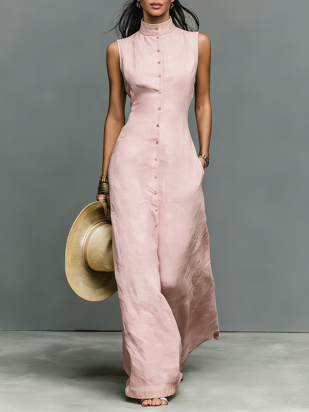 Close-up of pink sleeveless maxi dress with button details held by model in a studio.