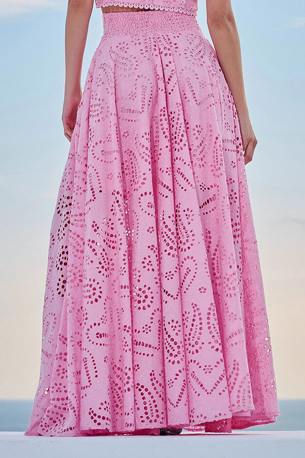 Back view of a pink embroidered high-waist maxi skirt worn by a model against a sky background.