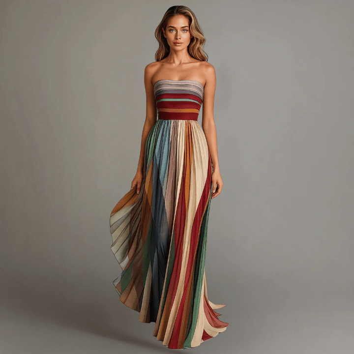 Model wearing an elegant sleeveless dress with multicolored vertical stripes, flowing down to the floor, in a studio setting.