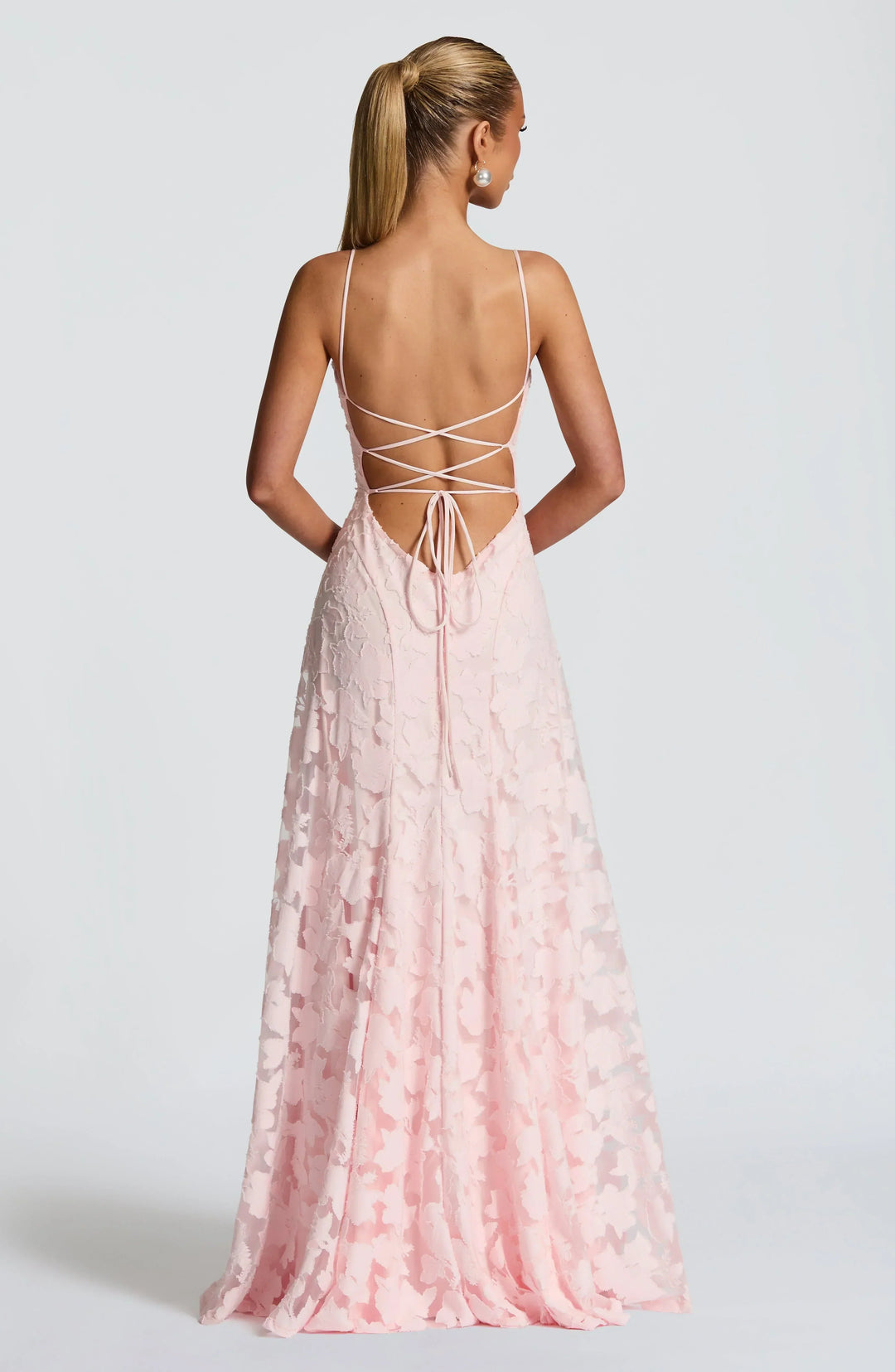 Back view of light pink maxi dress with criss-cross strap detailing in a studio setting.