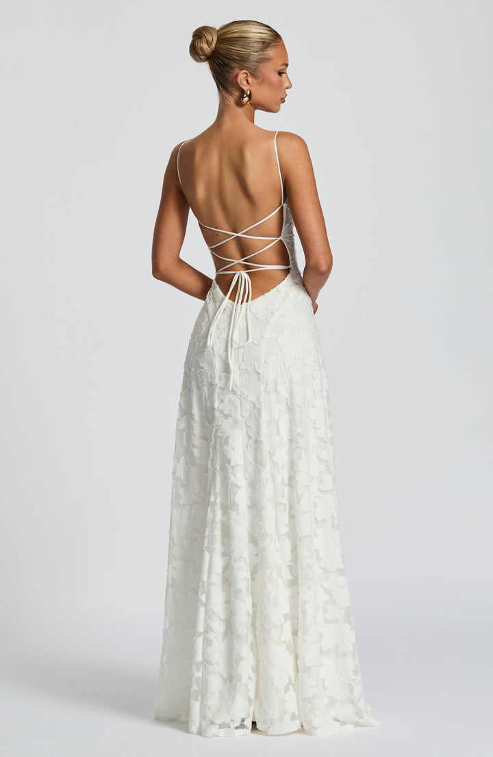 Back view of white maxi dress with criss-cross strap detailing in a studio setting.