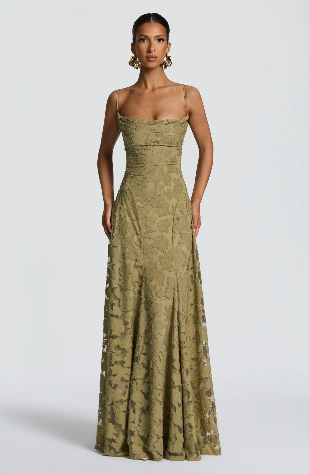 Elegant maxi dress in olive green with floral texture, thin straps, and floor-length design in a studio setting.