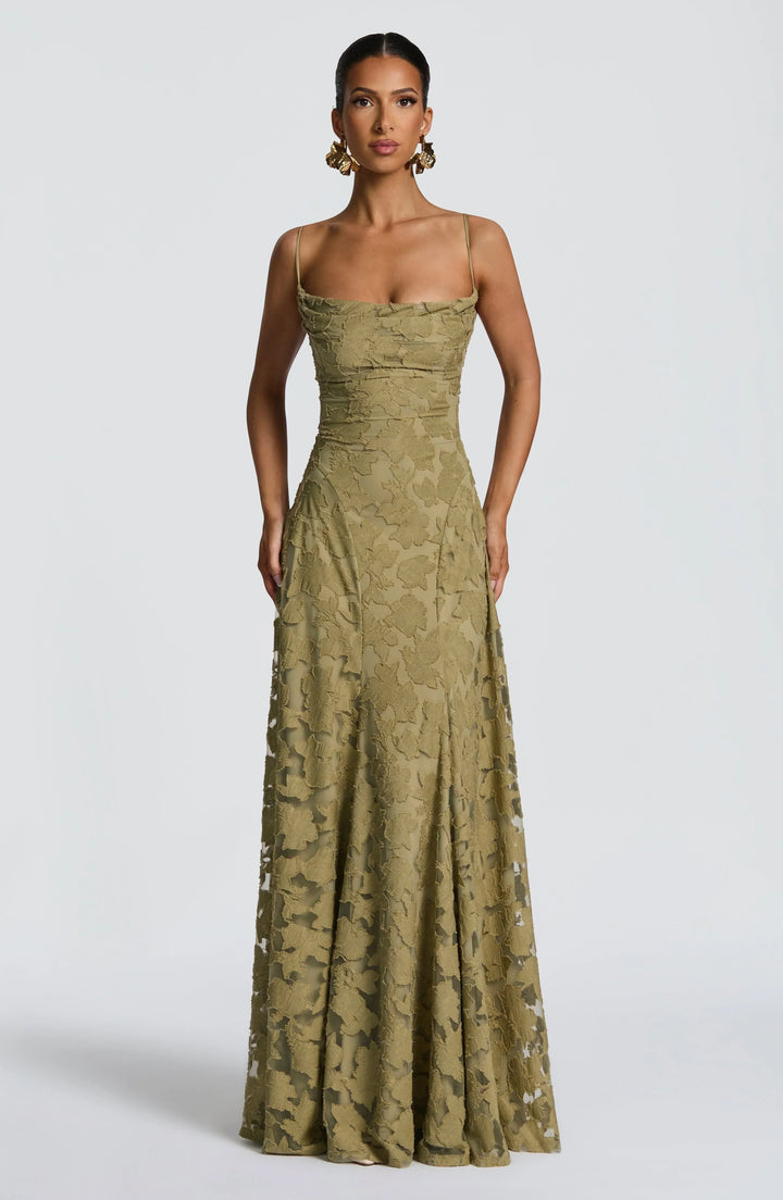 Elegant maxi dress in olive green with floral texture, thin straps, and floor-length design in a studio setting.