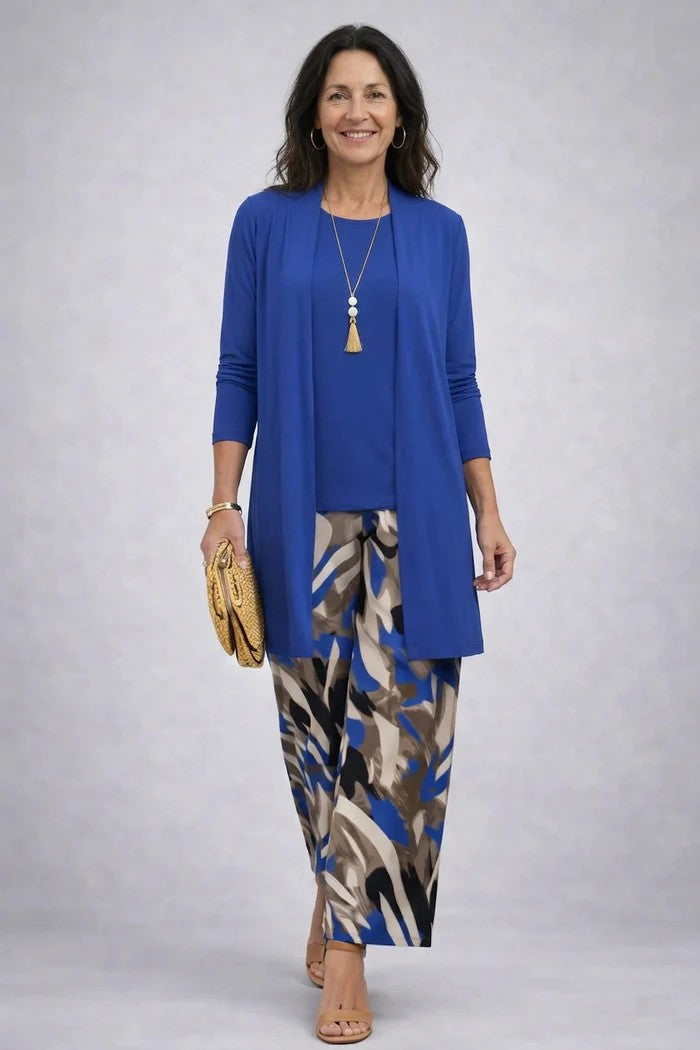 Woman wearing a vibrant blue three-piece set with patterned pants. Studio backdrop.