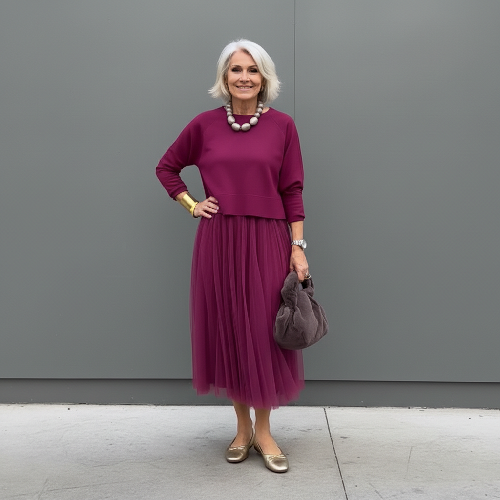 Stylish woman in burgundy pleated skirt set with beads, outdoor setting.