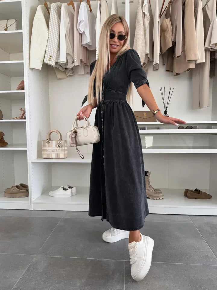 Black denim dress with buttons and tied sleeves, worn by a person with sunglasses and white sneakers, in a closet setting.